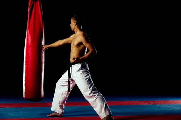 Boxer formação em um saco de pontapé no ginásio isolado em preto wal — Fotografia de Stock