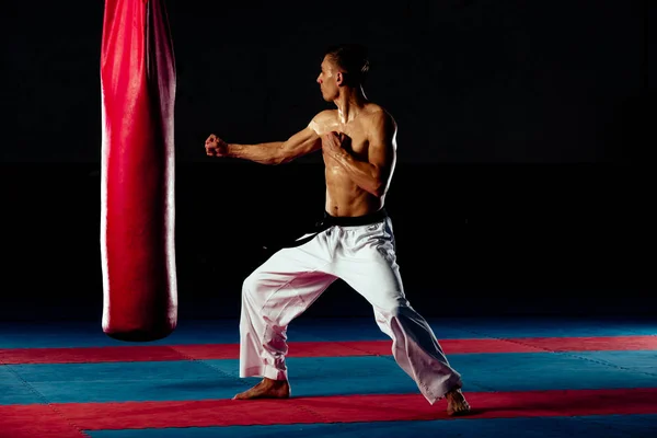 Jovem esportista caucasiano chutando saco de perfuração — Fotografia de Stock