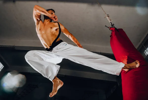 Entrenamiento de boxeador masculino está haciendo ejercicio con un saco de boxeo en el gimnasio — Foto de Stock