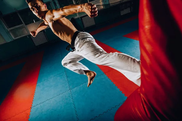 Entrenamiento de boxeador masculino está haciendo ejercicio con un saco de boxeo en el gimnasio —  Fotos de Stock