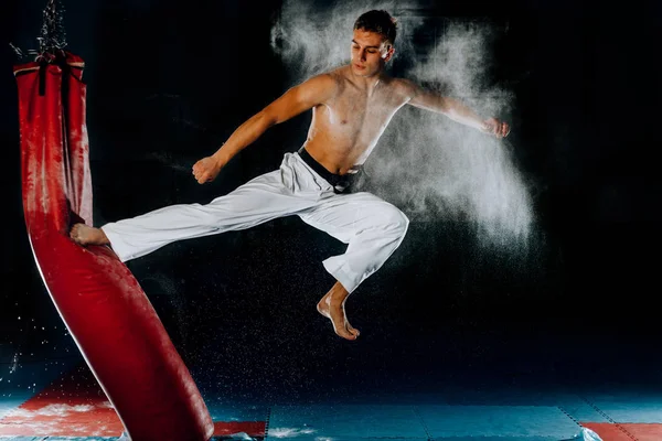 Hombre practicando boxeo en bolsa negra grande en gimnasio — Foto de Stock