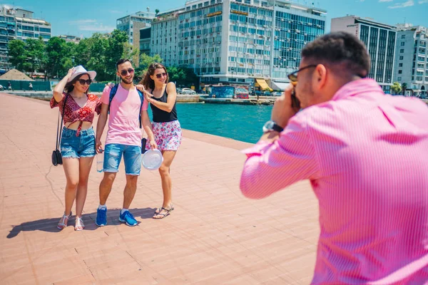 Quatro turistas tirando uma foto ao lado do mar, enquanto sendo casuall — Fotografia de Stock