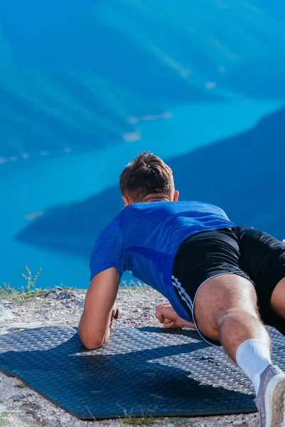Sterke mannelijke atleet doen plank tijdens het uitoefenen van zijn buikspieren op de top — Stockfoto