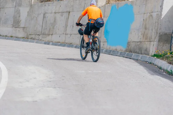 Atleta ciclista monta su bicicleta cuesta arriba, usando ciclismo profesional — Foto de Stock