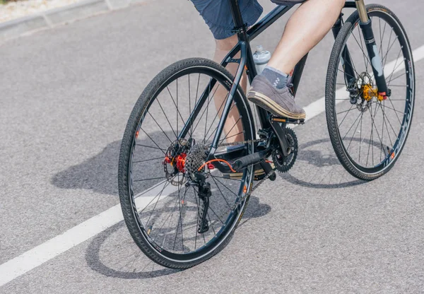 En kaukasiska manliga cyklist rider sin cykel uppförsbacke, bär yrke — Stockfoto