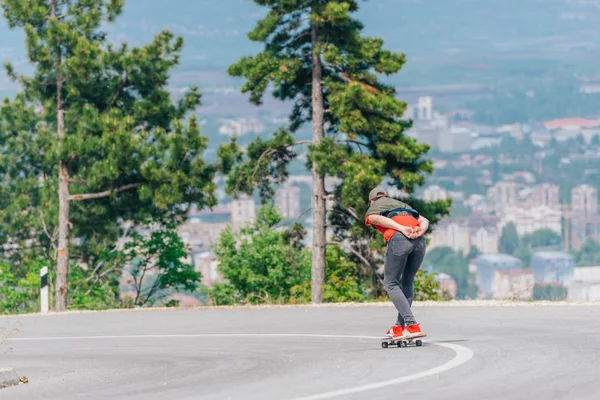 Tall athlete riding his longboard fast and steady downhill while — Stock Photo, Image