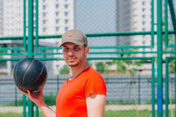 Retrato de un joven jugador de baloncesto fuerte sosteniendo un bas negro — Foto de Stock