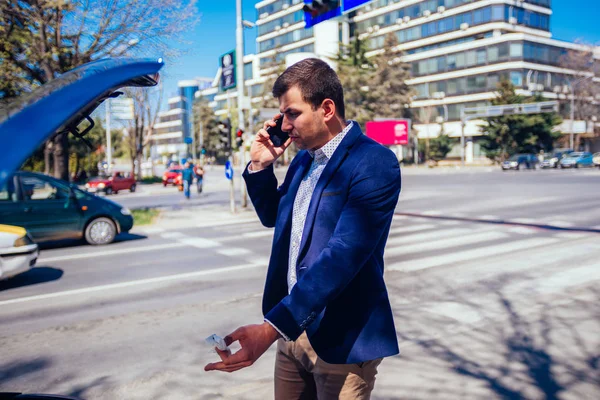 Genç Işadamı Arabasının Kaputunun Altına Bakarken Telefonla Konuşuyor — Stok fotoğraf