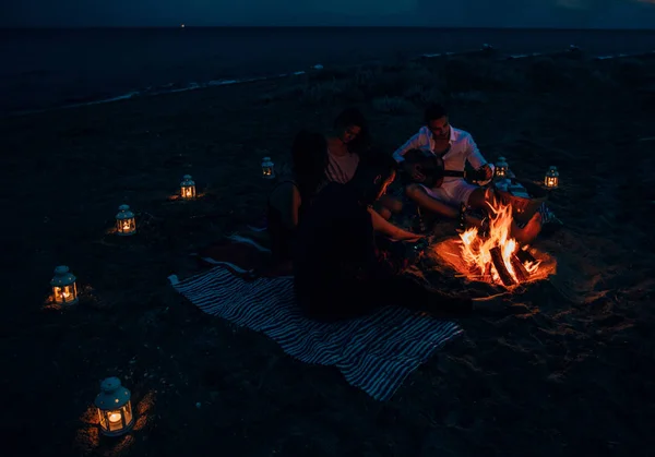 Friends enjoying music near campfire at night — Stock Photo, Image