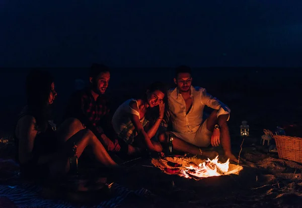 Die fröhlichen Menschen wärmen sich am Lagerfeuer die Hände. Nachts — Stockfoto