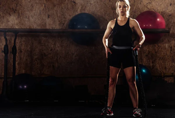 Mujer haciendo ejercicio con cuerdas de batalla en el centro crossfit — Foto de Stock