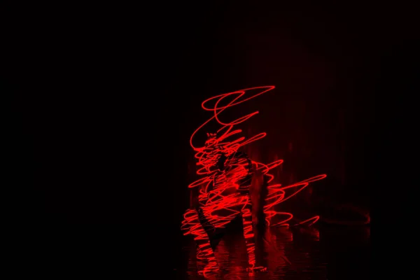 一个英俊的女舞者表演地狱的艺术表现 同时炫耀她的身体和大量的红色激光灯 — 图库照片