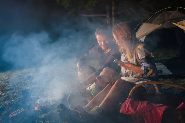 Genç çift kamp ateşinde sosis pişiriyor ve bira içiyor. — Stok fotoğraf