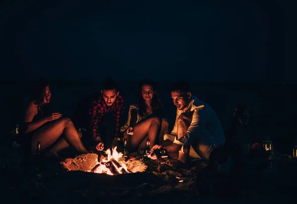 Arkadaşların kumsalda kamp ateşinin yanında müzik dinliyorlar. — Stok fotoğraf