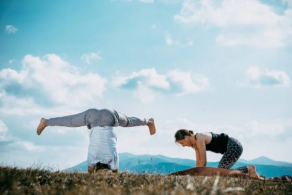 ヨガのワークアウトを行う強力で柔軟な若いカップル 午前中に山の練習ペアヨガの男と女 — ストック写真