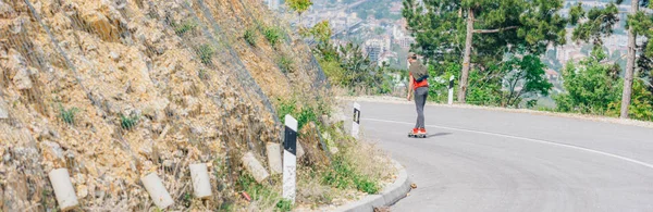 Großer junger männlicher fitter Longboarder springt von seinem Longboard, während — Stockfoto