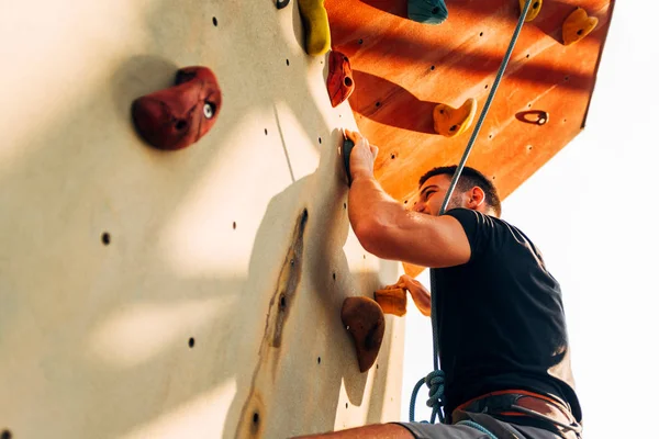 Ung sportig man klättrar upp på praxis mount vägg utomhus — Stockfoto