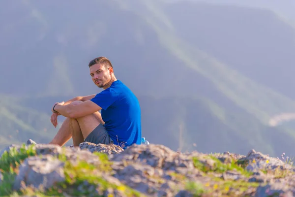 Avontuurlijk man zitten op de top van een berg en genieten van de be — Stockfoto