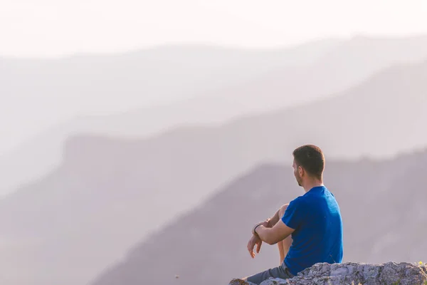 Uomo avventuroso seduto sulla cima di una montagna e godendo il be — Foto Stock