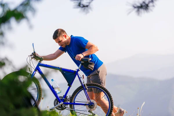 Mountain biker wearing a blue shirt is pushing his bike through — Stock Photo, Image