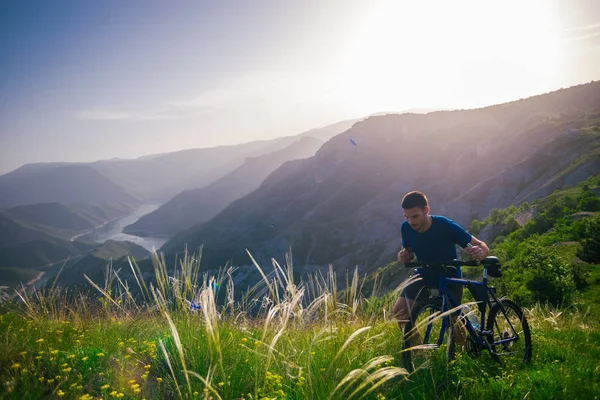 Perspective of a fit mountain biker pushing his bike uphill with — Stock Photo, Image
