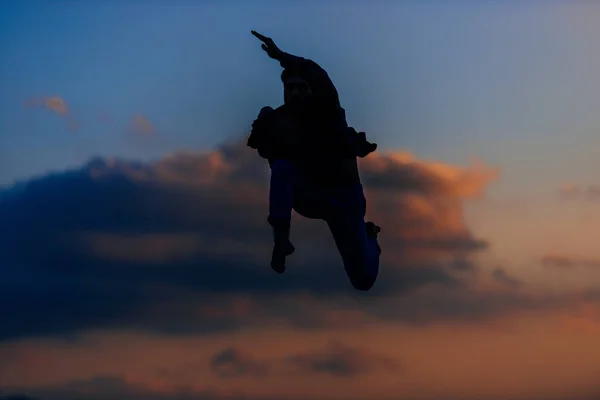 Silhouet Van Een Knappe Springende Man Tegen Bewolkte Lucht Avonds — Stockfoto
