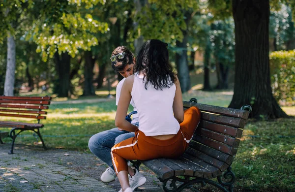 Young couple in love sitting together on a bench in summer park — ストック写真