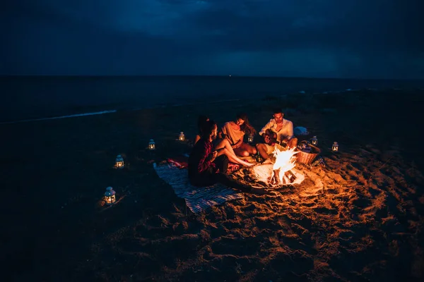Şenlik ateşinin yanında elini ısıtan mutlu insanlar. Gece vakti. — Stok fotoğraf
