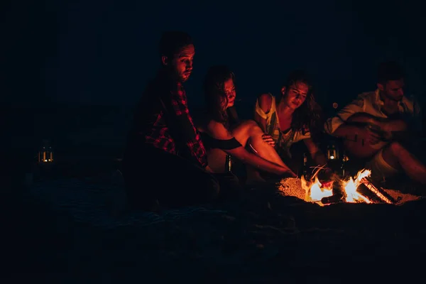 Friends enjoying music near campfire at night on the sandy beach — Stock Photo, Image