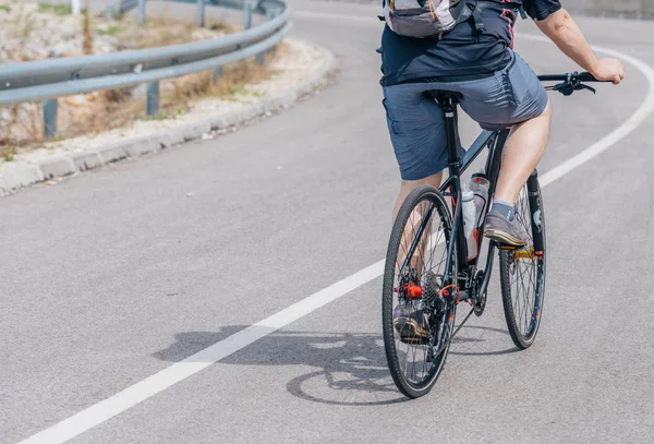 Un motociclista caucasico di sesso maschile guida la sua moto in salita, indossando professione — Foto Stock