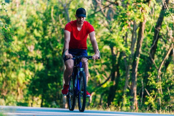 Fit cyklista jezdí na kole (kole) na prázdné silnici v přírodě — Stock fotografie