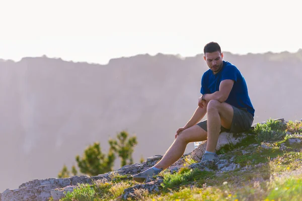 Avontuurlijk man zitten op de top van een berg en genieten van de be — Stockfoto