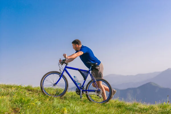 Fit férfi hegyi kerékpáros nyomja a kerékpár felfelé, miközben keres ex — Stock Fotó