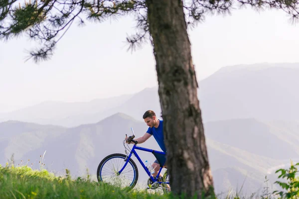 Mountainbiker in een blauw shirt duwt zijn fiets door — Stockfoto