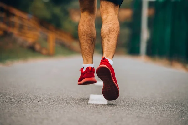 男性のトライアスロンランナーのランニングシューズ 道路上で実行されている足の閉鎖 — ストック写真