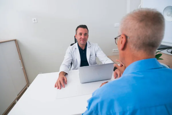 Schöner Doktor und sein älterer Patient im Gespräch — Stockfoto