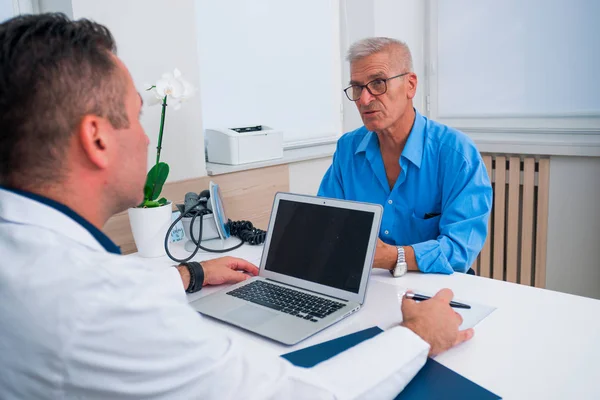 Schöner Doktor und sein älterer Patient im Gespräch — Stockfoto