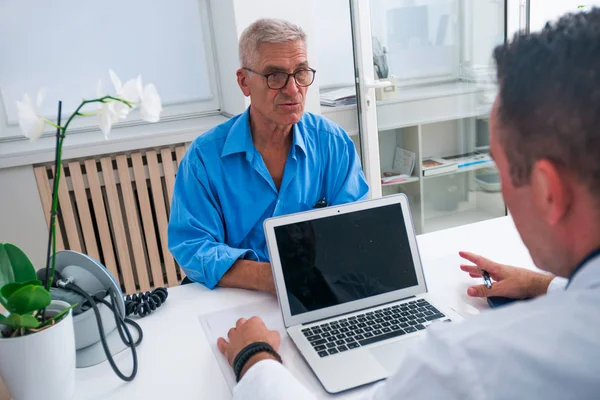 Schöner Doktor und sein älterer Patient im Gespräch — Stockfoto