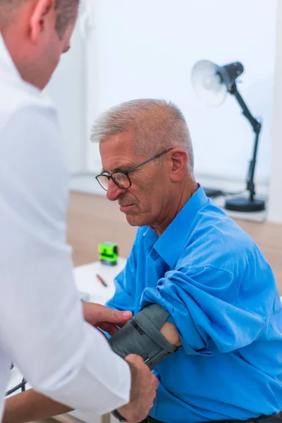 Ein kaukasischer Arzt misst den Blutdruck seines älteren Kumpels — Stockfoto