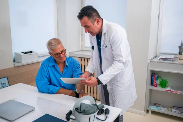 El médico caucásico de mediana edad le explica a su paciente mayor su situación. —  Fotos de Stock
