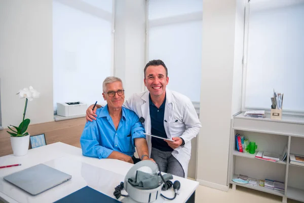 Her ikisi de gülümserken bir doktor kıdemli hastasına sarılır. — Stok fotoğraf