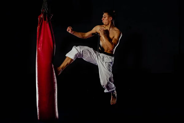 Muscoloso ragazzo perfezionare la sua abilità di pugilato su borsa pesante rossa — Foto Stock