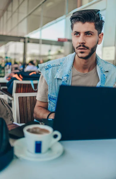Schöner Mann Schaut Auf Laptop Während Wartehalle Sitzt Und Kaffee — Stockfoto