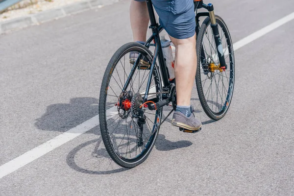 Un ciclista caucásico monta su bicicleta cuesta arriba, llevando profesión —  Fotos de Stock