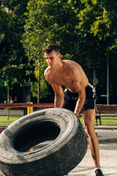 Handsome Hispanic young man halfway from flipping a tire in a cross-training gym