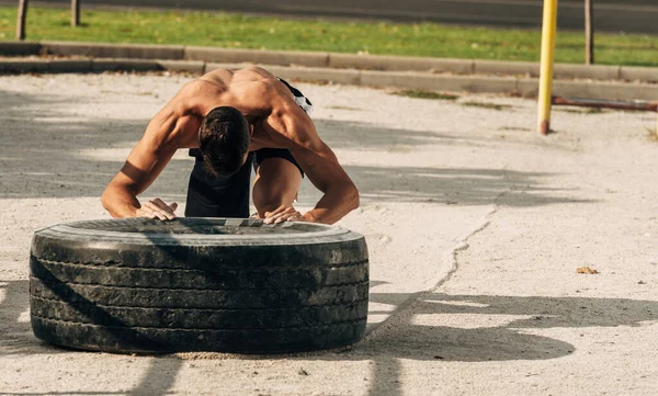 赤裸的年轻健康男子在健身房翻动沉重的轮胎 运动员 健美理念 — 图库照片