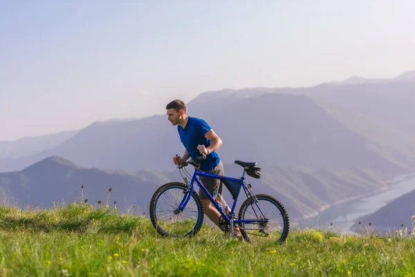 Fáradt fitt mountain bike-os nyomja a kerékpár felfelé a tetején t — Stock Fotó