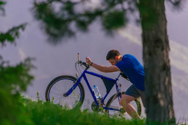 劳累的骑自行车的人一边把汗从脸上擦掉，一边推挤着他的自行车。 — 图库照片