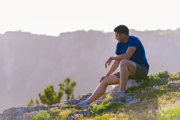 Homem aventuroso sentado no topo de uma montanha e apreciando o ser — Fotografia de Stock