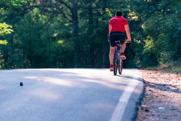一个高大英俊的骑自行车的人在日落时骑着他的自行车 — 图库照片